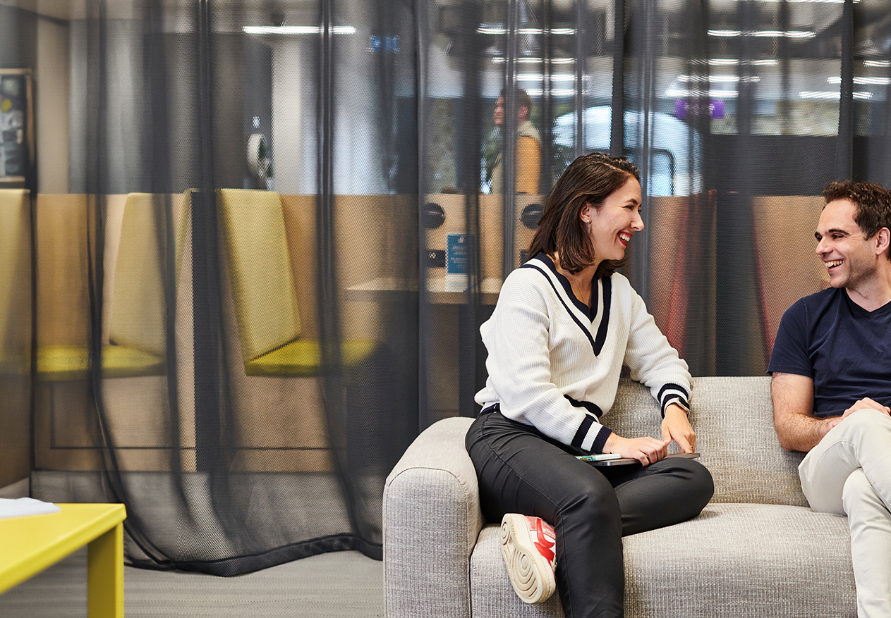 Two Deliveroo employees talking together on a sofa