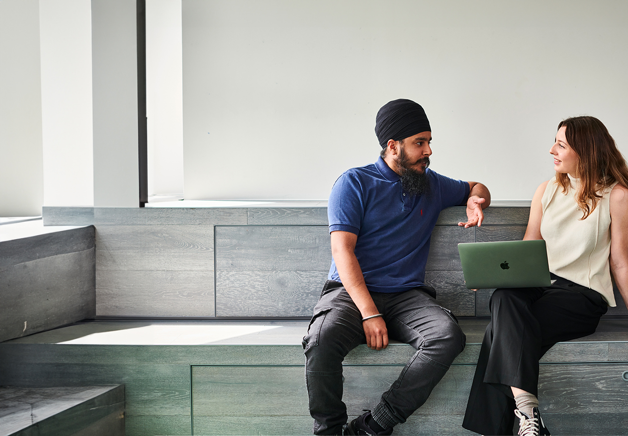 Two Deliveroo employees sitting on a sofa talking