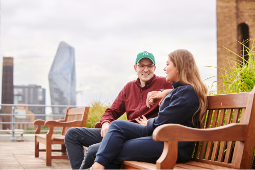 Two Deliveroo employees outside on a bench