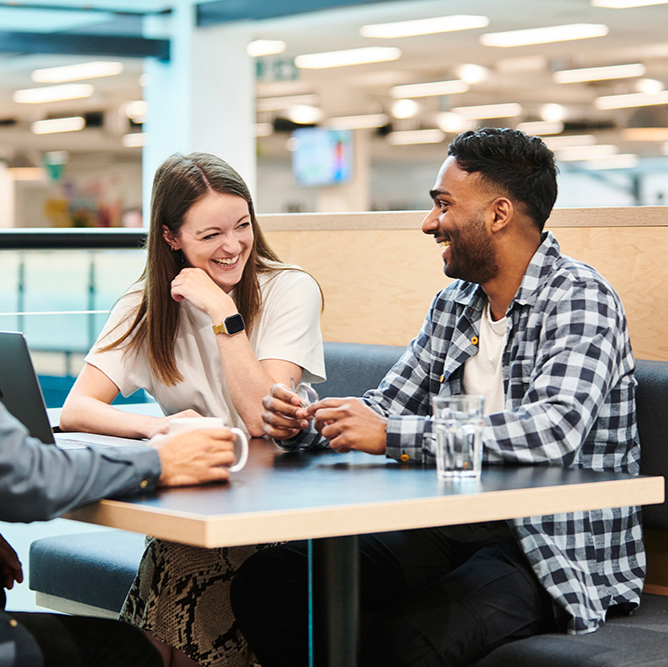 Two Deliveroo employees laughing together at a desk