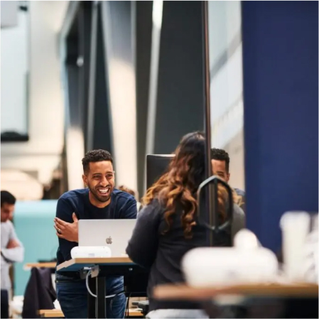 Man smiling at his colleague in a busy office