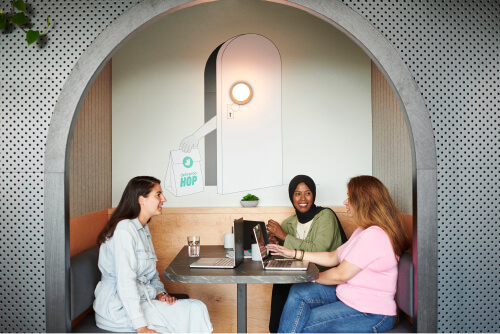 Group of 3 Deliveroo employees sat together with laptops