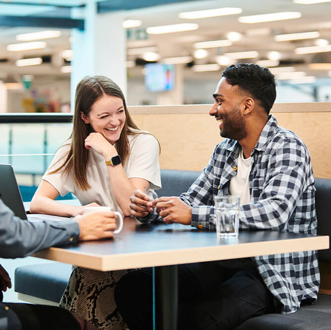 Two employees laughing together whilst sat at a table
